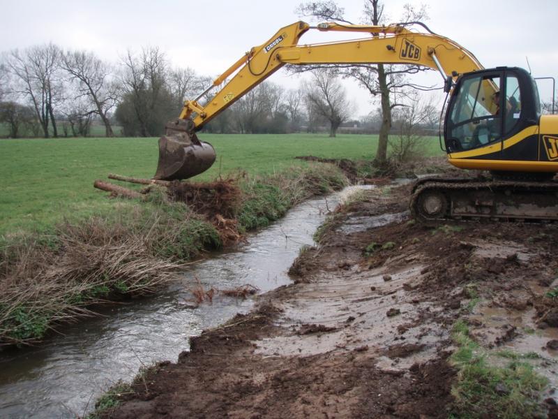 Excavator installing root wads into the brook and re-profiling the banks